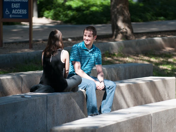 Two students sitting outside and talking.