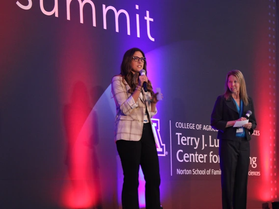 woman standing on stage giving a presentation