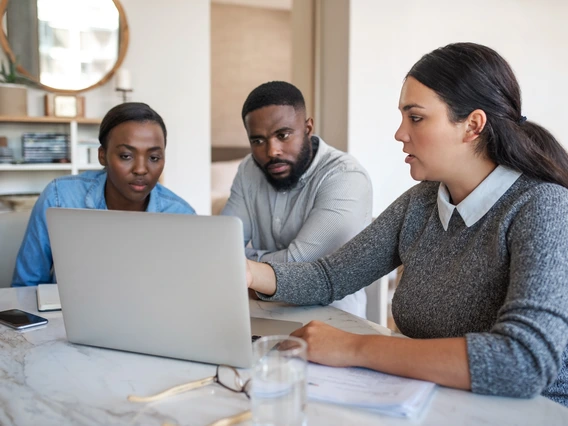 A financial planner showing a couple options on a laptop. 