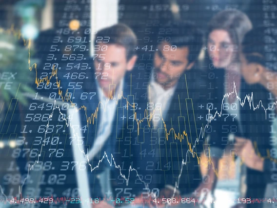 A group of people in business suits talking behind a transparent screen of stock tickers and prices.