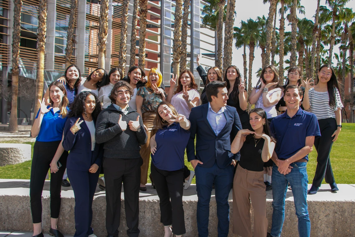 group of 18 students posing in front of a building