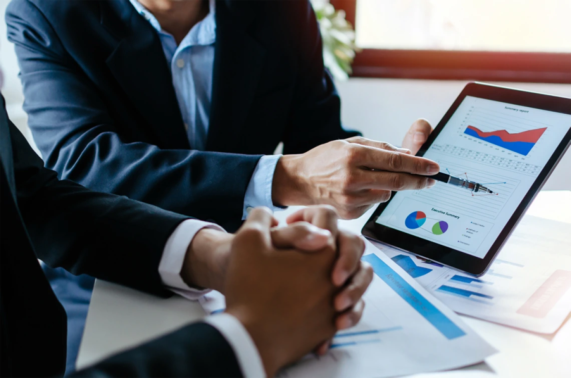 Picture of man showing another man graphs on a screen