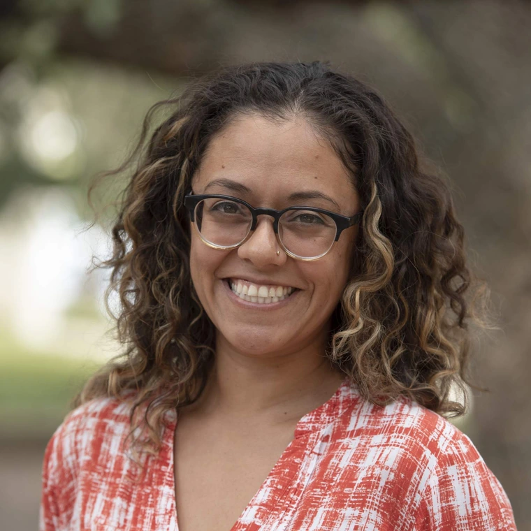 woman with curly hair and glasses smiling