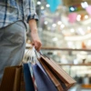 A woman stands in a mall holding shopping bags