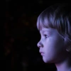 Close-up of little boy whose face is lit by a TV screen