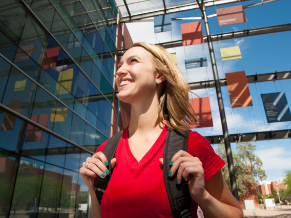 A happy female student in front of a building